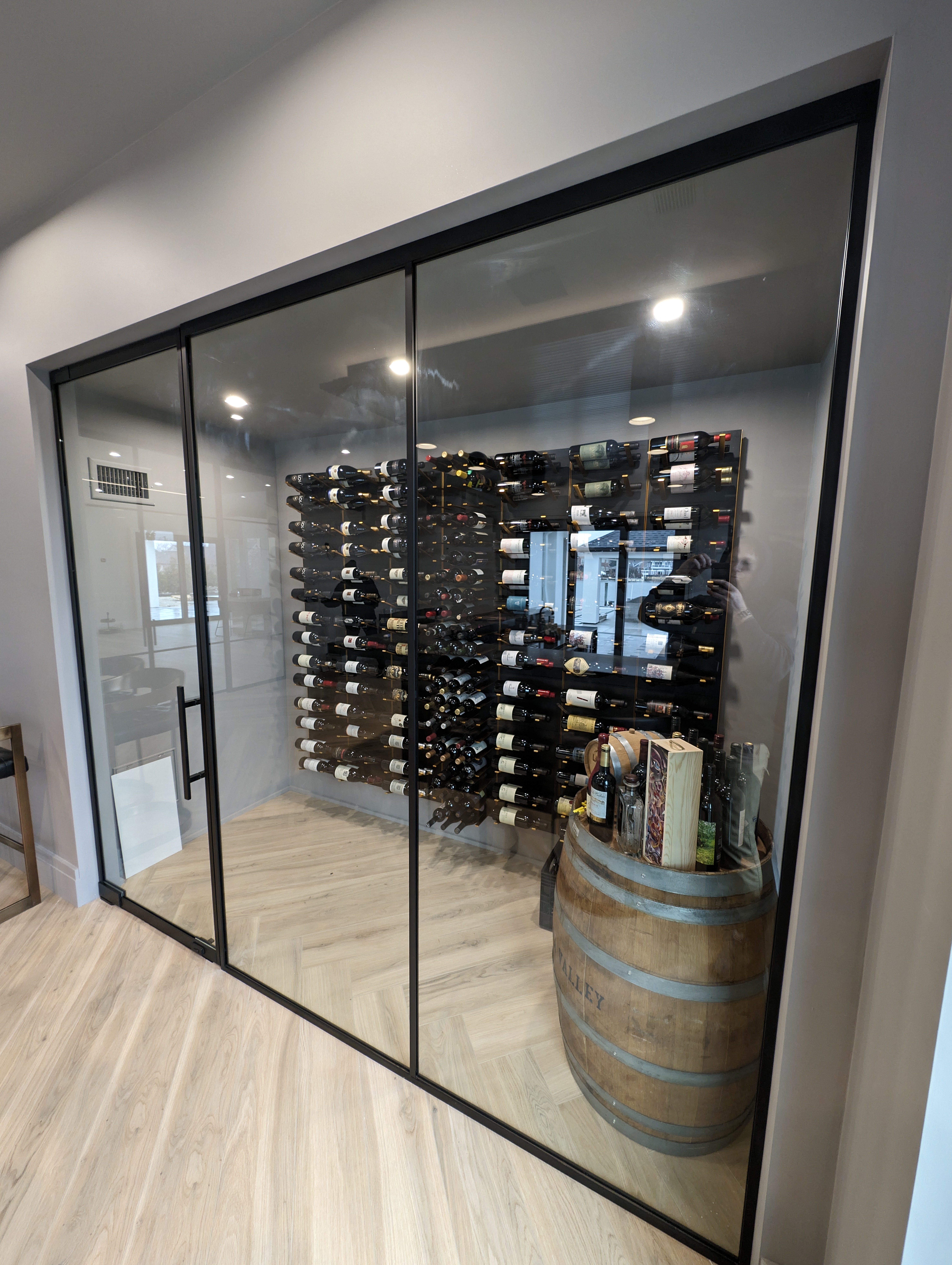 Completed custom glass wine enclosure with floor-to-ceiling panels and wine barrel — WiseGlass NY