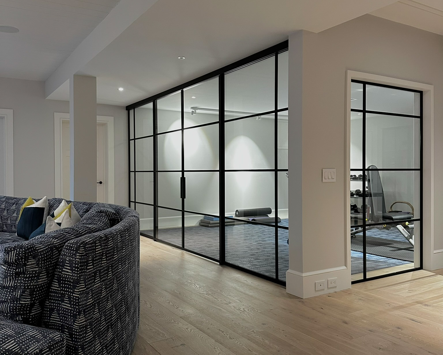Before — open lower level of a Sagaponack NY estate, gym area exposed to living space prior to glass partition installation by WiseGlass NY