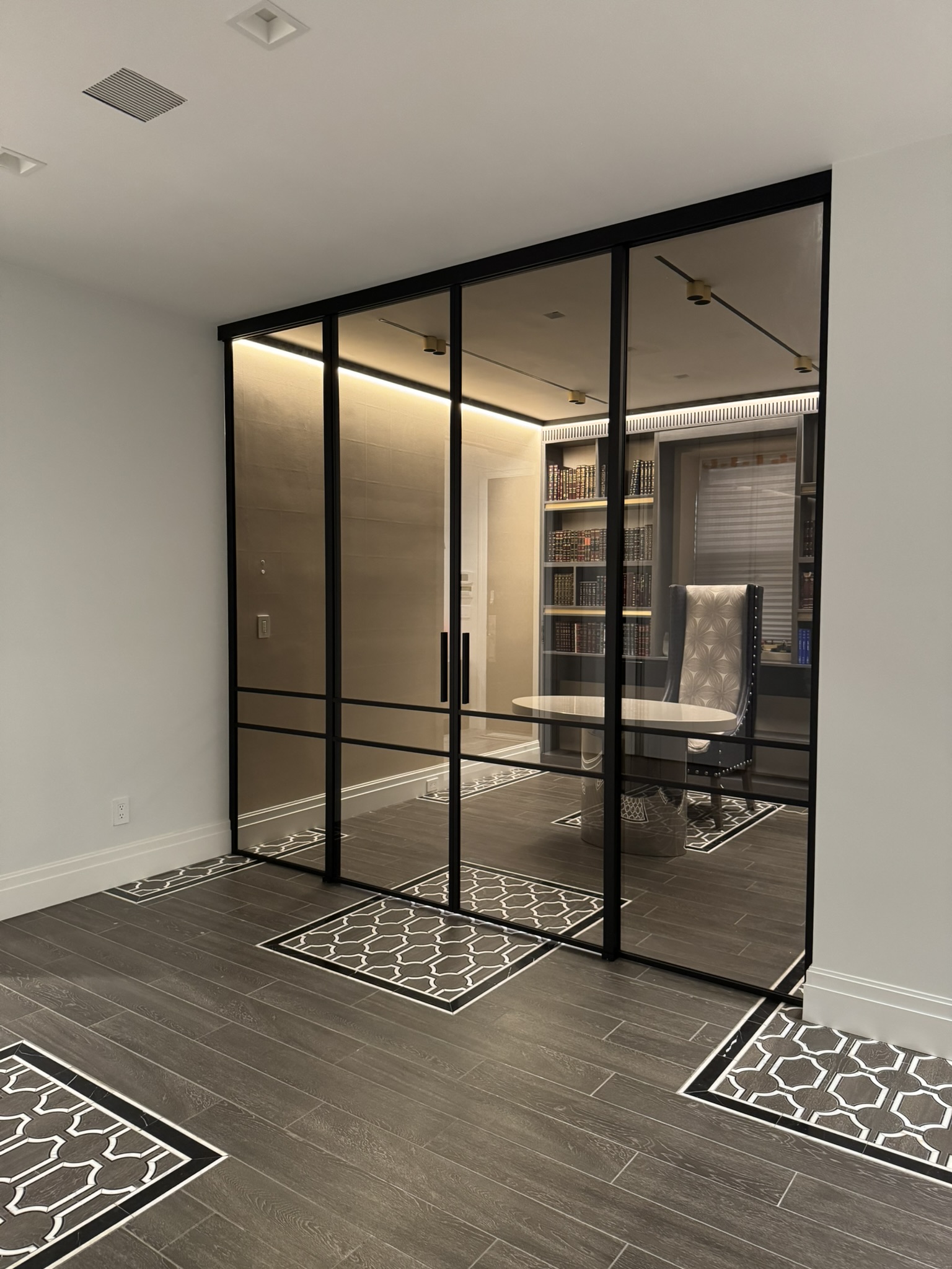 Custom bronze tinted glass partition with black matte frame enclosing private library study — WiseGlass NY